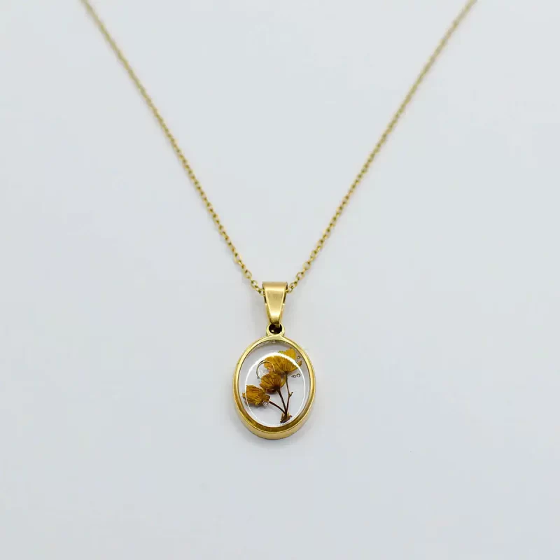 Gold-plated oval pendant necklace with real yellow dried flowers, displayed on a white background.