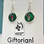 Zilverkleurige ronde oorbellen met roze bloem op groene achtergrond.