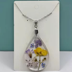 Druppelvormige geperste bloemen ketting met paarse, gele en witte echte bloemen in heldere hars aan zilverkleurige ketting