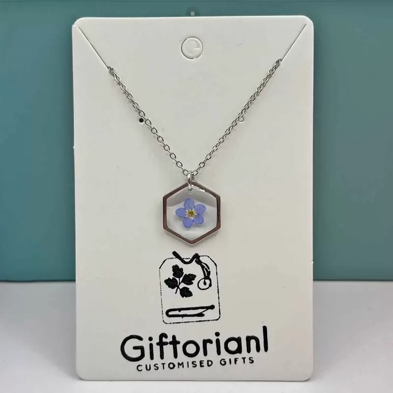 Zilverkleurige hexagon hanger met blauw vergeet-mij-nietje.