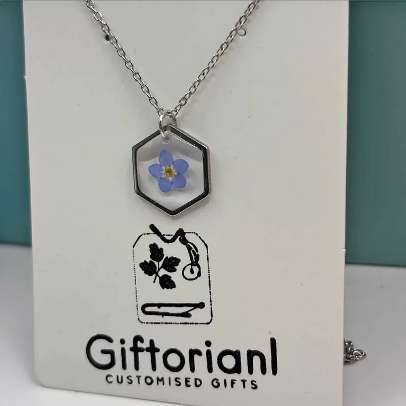 Zilverkleurige hexagon hanger met blauw vergeet-mij-nietje.
