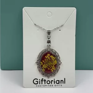 Ovale vintage hanger met gele bloemen op rode achtergrond.