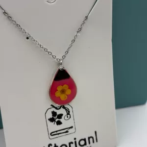 Zilverkleurige druppelvormige hanger met gele bloem in roze hars.