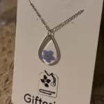 Vrouw draagt de handgemaakte RVS ketting met een hanger met daarin een echt vergeet-mij-nietje.