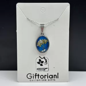 Handgemaakte blauwe droogbloemen ketting met ovale zilverkleurige hanger en witte bloemetjes op Giftorianl kaart.