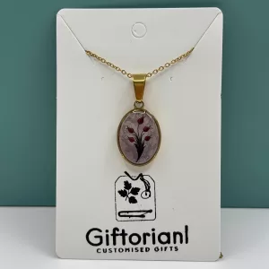 Handgemaakte tulpen ketting met ovale goudkleurige hanger en rood tulpdesign op witte kaart.