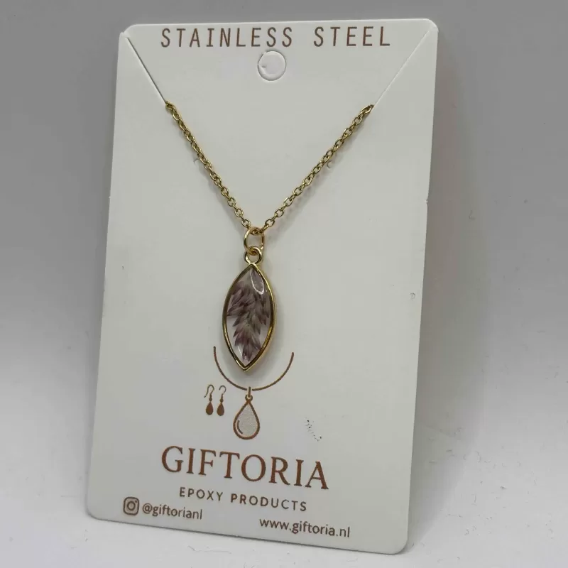 Close‑up goudkleurige marquise hanger met paarse droogbloemen in epoxy.