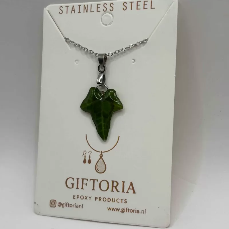 Speciaal cadeau ketting met groene bladhanger gedragen boven een beige trui.